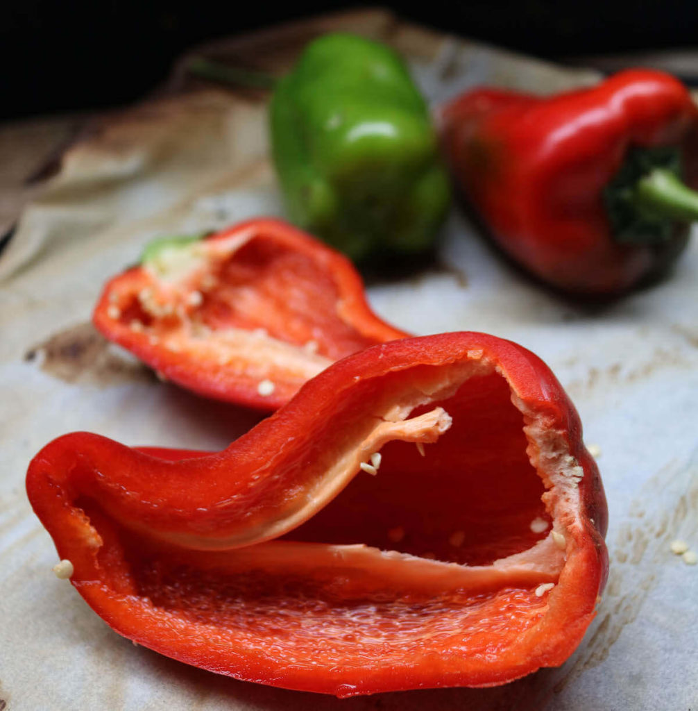 step 1 on making keto stuffed peppers - cut peppers in half and bake